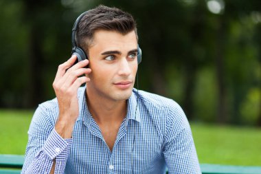 genç adam bir Şehir Parkı içinde müzik dinlemek