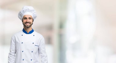 Geniş, parlak bir arkaplan önünde gülümseyen şef.