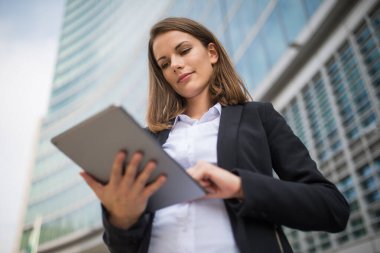 Ofisinin önünde tablet kullanan genç bir kadının portresi.