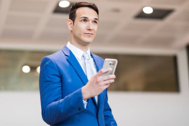 İş adamı akıllı telefonunu içeride kullanıyor.