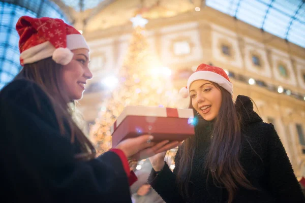 Jonge Lachende Vrouwen Met Kerstmuts Die Cadeautjes Uitwisselen Voor Een — Stockfoto