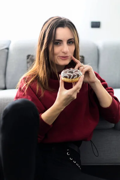 Mujer Joven Comiendo Donut Sentado Alfombra Cerca Sofá — Foto de Stock