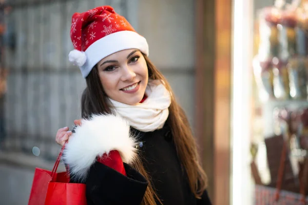 圣诞节前 年轻女人拿着购物袋 在商店门口笑着 — 图库照片