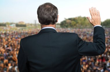Politikacı konuşuyor ve elini kaldırarak yemin ediyor.