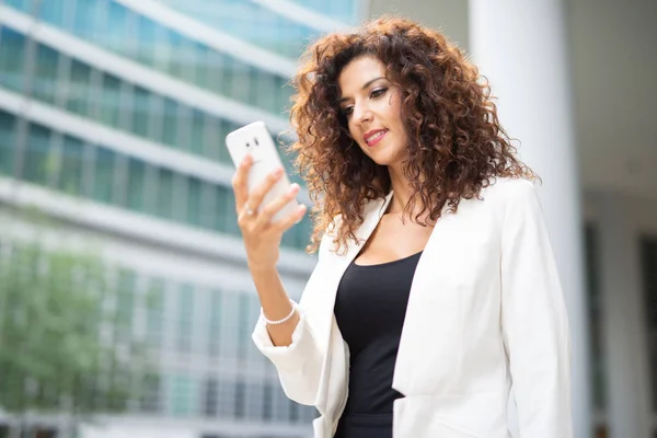 Uśmiechnięta Bizneswoman Korzystająca Telefonu Komórkowego Podczas Spaceru Biura — Zdjęcie stockowe