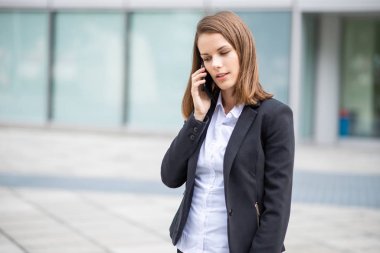 Genç iş kadını cep telefonuyla konuşuyor.