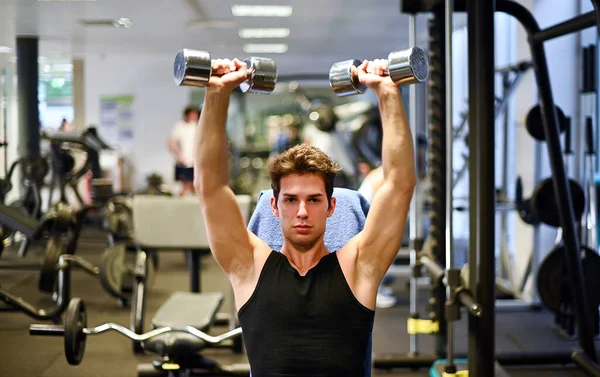 健美运动员举起哑铃 在体育馆里锻炼他的胳膊和肩膀 — 图库照片