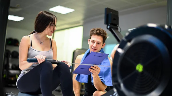 Young Woman Working Out Rowing Machine Personal Trainer Explaining Technique — Stock Photo, Image