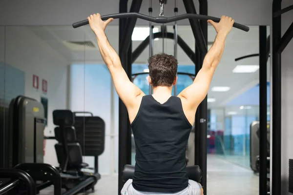 男人在健身房里用轻便的机器来训练他的肩膀和背 锻炼身体和自然健身的概念 — 图库照片