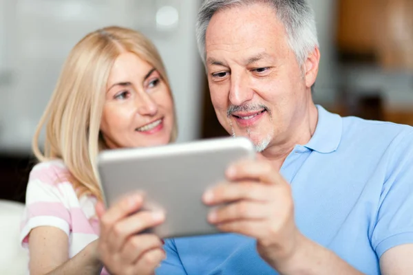 Gülümseyen Bir Olgun Çift Dijital Tablet Kanepe Evde Kullanma Portresi — Stok fotoğraf