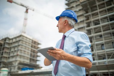 Site manager using his digital tablet in front of a construction site