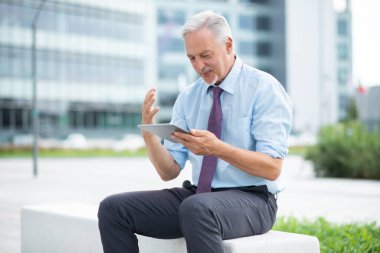 İşadamı ofisinin önünde tabletine bakıyor.