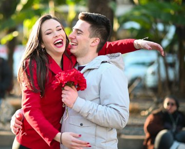 Young woman hugging her boyfriend because he gave her flowers - Valentine's Day concept