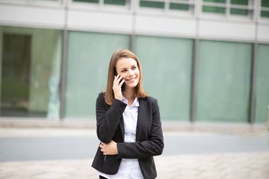 Genç iş kadını cep telefonuyla konuşuyor.