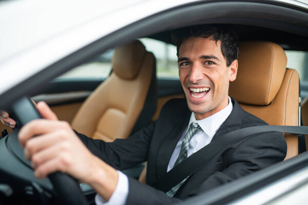 Smiling businessman driving his new white car