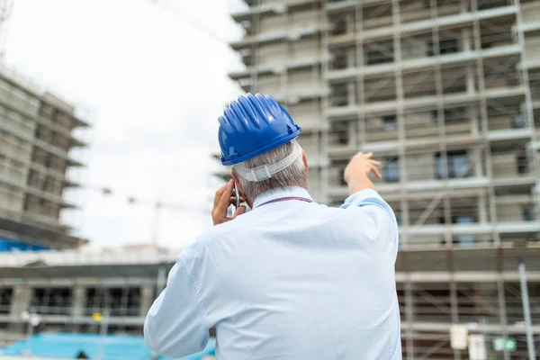 건축가 관리자가 휴대폰으로 얘기하고 현장에 손가락을 가리키는 — 스톡 사진