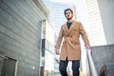 Modern bir şehirde merdivenlerden inen yakışıklı genç adam.