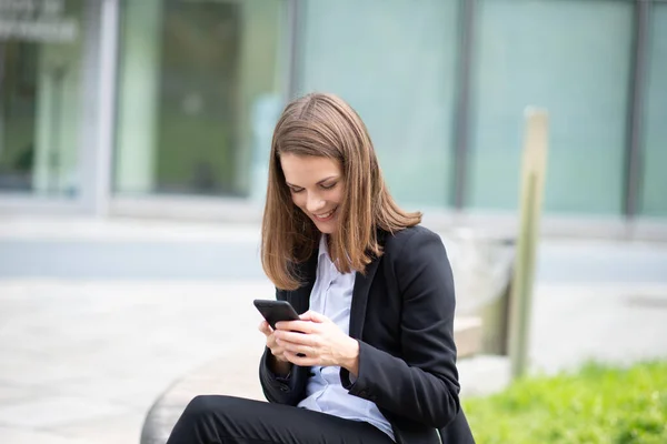 Obchodní Žena Pomocí Svého Mobilního Telefonu Zatímco Sedí Lavičce Před — Stock fotografie