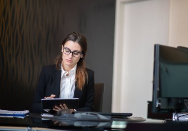 İş kadını şirket ofisinde tablet kullanıyor.