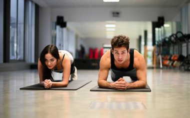 Spor salonunda şınav çeken iki sporcu.