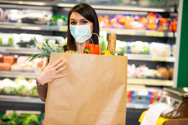 Masked woman holding an healthy food bag in a grocery store