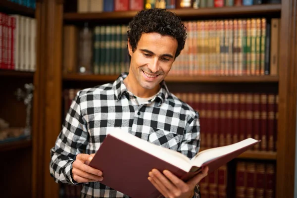 Uomo Sorridente Che Legge Libro Nella Sua Biblioteca Casa — Foto Stock