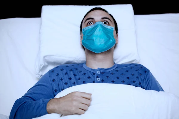 マスクを身に着けている間彼のベッドで寝るしようとしている不眠症の男の肖像画 コロナウイルス隔離の概念 — ストック写真