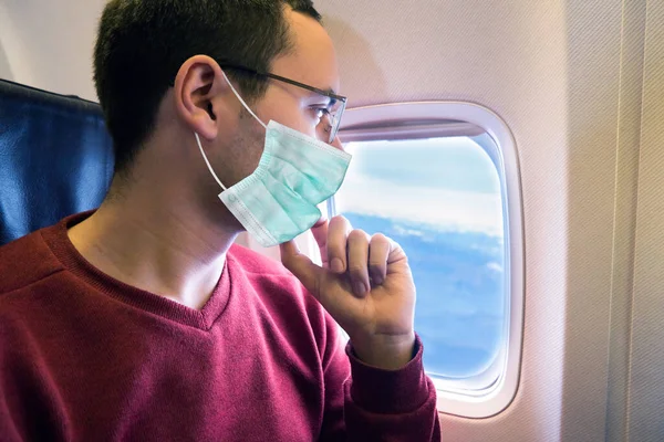 飛行中に外を見る覆面の乗客コロナウイルスパンデミックの概念 — ストック写真