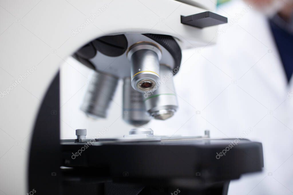 Scientist using microscope in a laboratory, coronavirus medical research concept