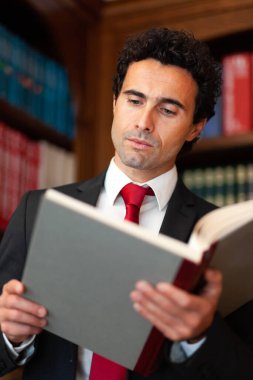 Avukat ofisinde kitap okuyor. 