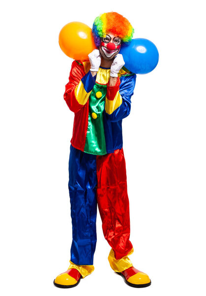 Full length portrait of a male clown in costume holding bunch of balloons isolated on white background