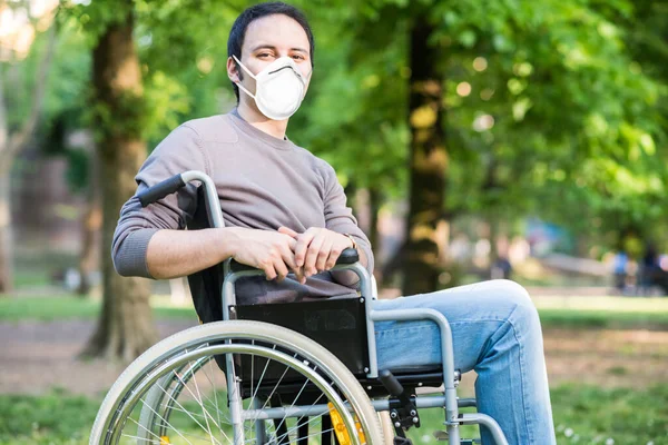 コロナウイルスのパンデミックの間の公園の車椅子に仮面の男の肖像画 — ストック写真