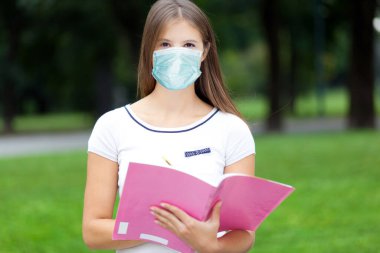Açık havada maske takan güzel bir üniversite öğrencisi, koronavirüs konsepti.