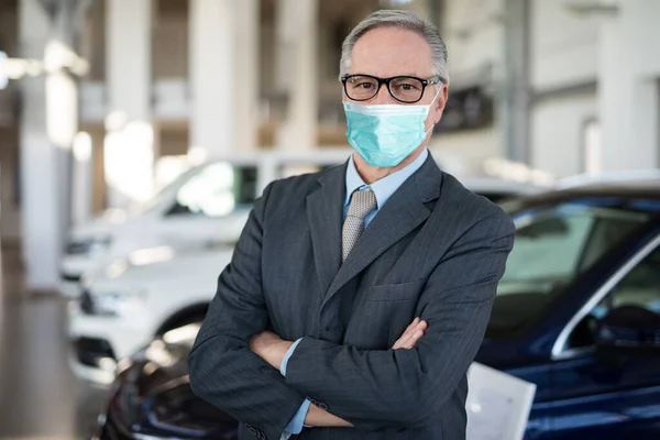 Masked car dealer principal inside showroom during coronavirus pandemic