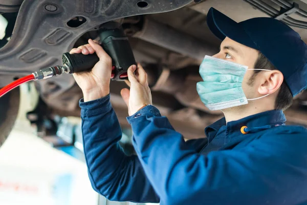 マスク コロナウイルスの概念を身に着けている自動車修理店で車のホイールを変更する機械 — ストック写真