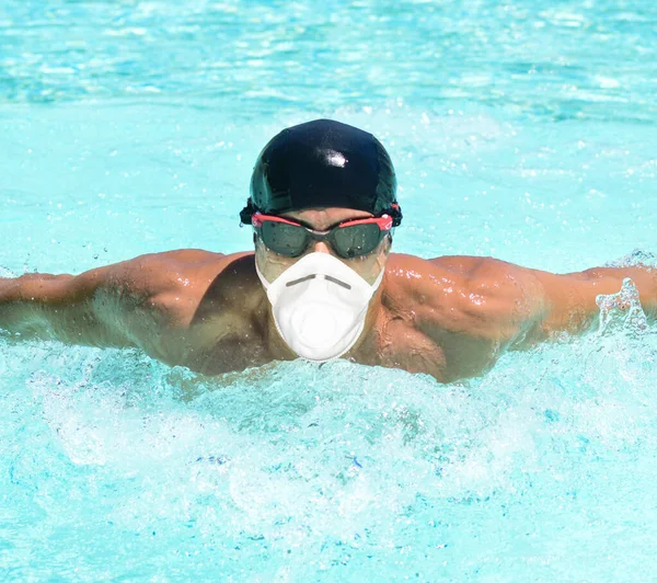 Masked man swimming in a pool, coronavirus pandemic sport concept