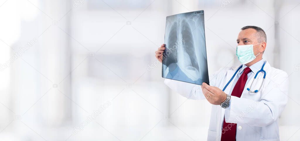 Doctor wearing a mask while holding a lung radiography, coronavirus and pneumonia concept