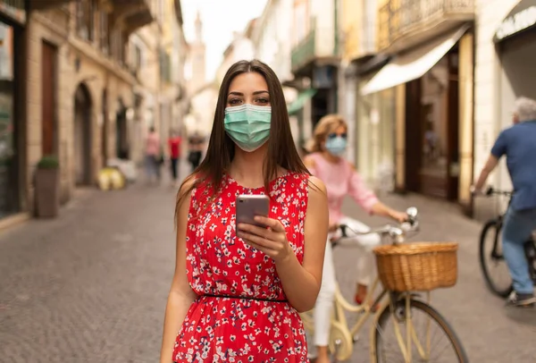 Mujer Joven Enmascarada Caminando Una Ciudad Mientras Usa Teléfono Móvil —  Fotos de Stock