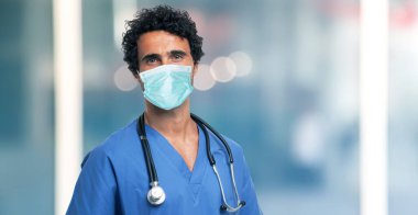 Maskeli bir doktor, parlak mavi bir arka plan.