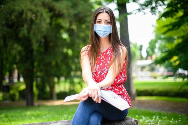 Hermosa Estudiante Universitaria Leyendo Libro Banco Parque Usando Una Máscara —  Fotos de Stock