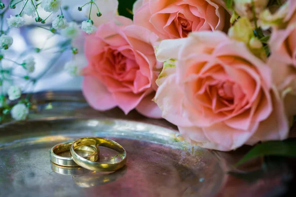 Обручальные кольца перед церемонией, с украшенными бокалами шампанского и розами — стоковое фото