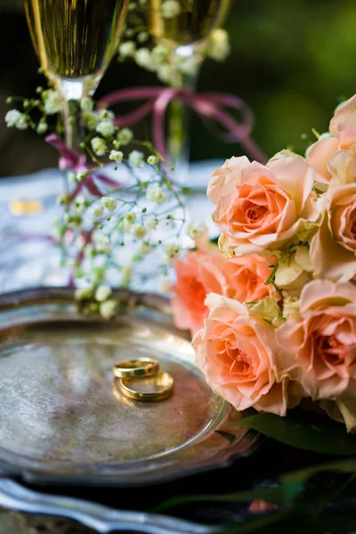 Обручальные кольца перед церемонией, с украшенными бокалами шампанского и розами — стоковое фото
