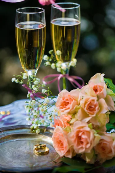 Obrączki ślubne przed ceremonią, zdobione kieliszki szampana i róże — Zdjęcie stockowe