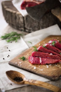Ahşap kesme tahtası biberiye yaprağı ile ham sığır eti dilimleri