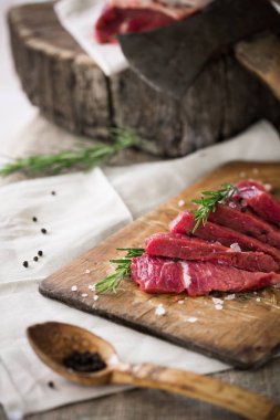 Ahşap kesme tahtası biberiye yaprağı ile ham sığır eti dilimleri