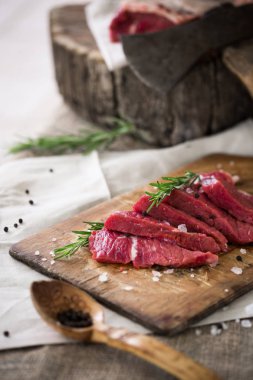 Ahşap kesme tahtası biberiye yaprağı ile ham sığır eti dilimleri