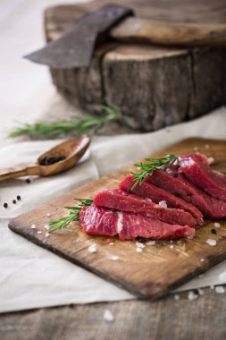 Ahşap kesme tahtası biberiye yaprağı ile ham sığır eti dilimleri