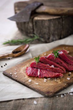Ahşap kesme tahtası biberiye yaprağı ile ham sığır eti dilimleri