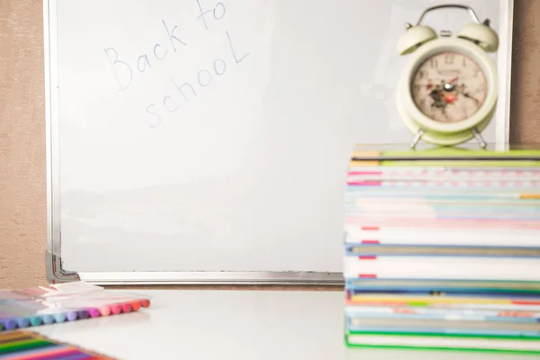 Mesa branca com pilha de livros coloridos, despertador e material escolar, espaço de cópia, tempo de estudo em casa para crianças — Fotografia de Stock