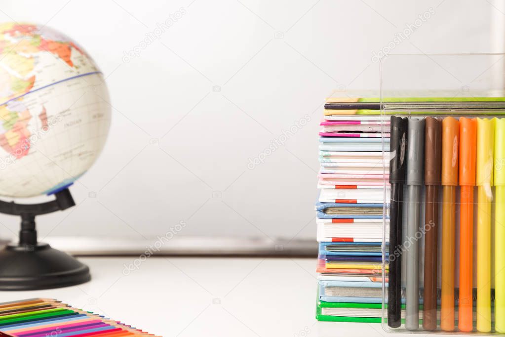 White table with stack of colorful books, alarm clock and schoolsupplies, copy space, children home schooling study time